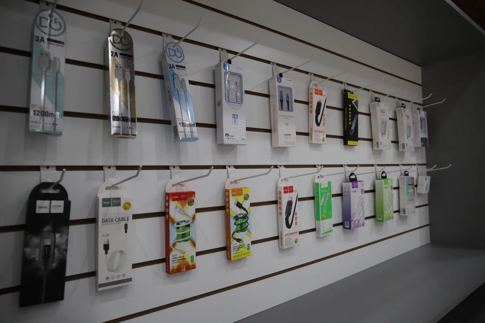 Cables y cargadores colgados en la pared de accesorios del local