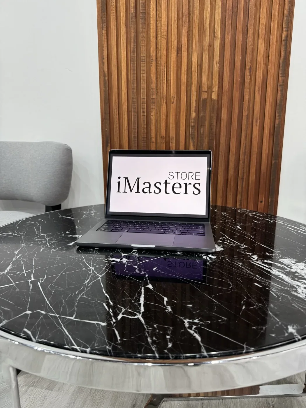 Una MacBook con el logo de iMasters Store en la pantalla, sobre una mesa de mármol del local