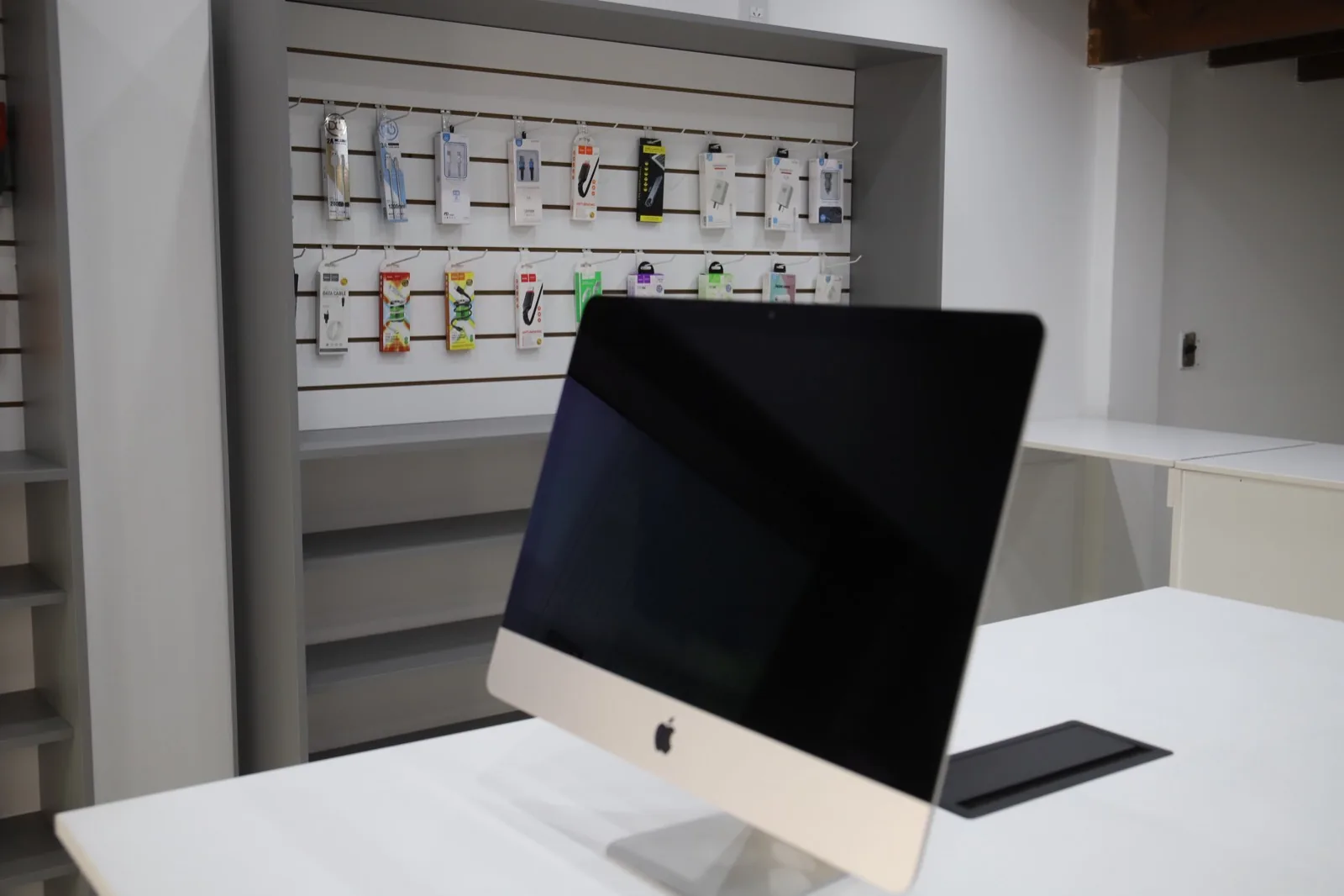 Un iMac en el salón de iMasters Store, frente a la pared de accesorios