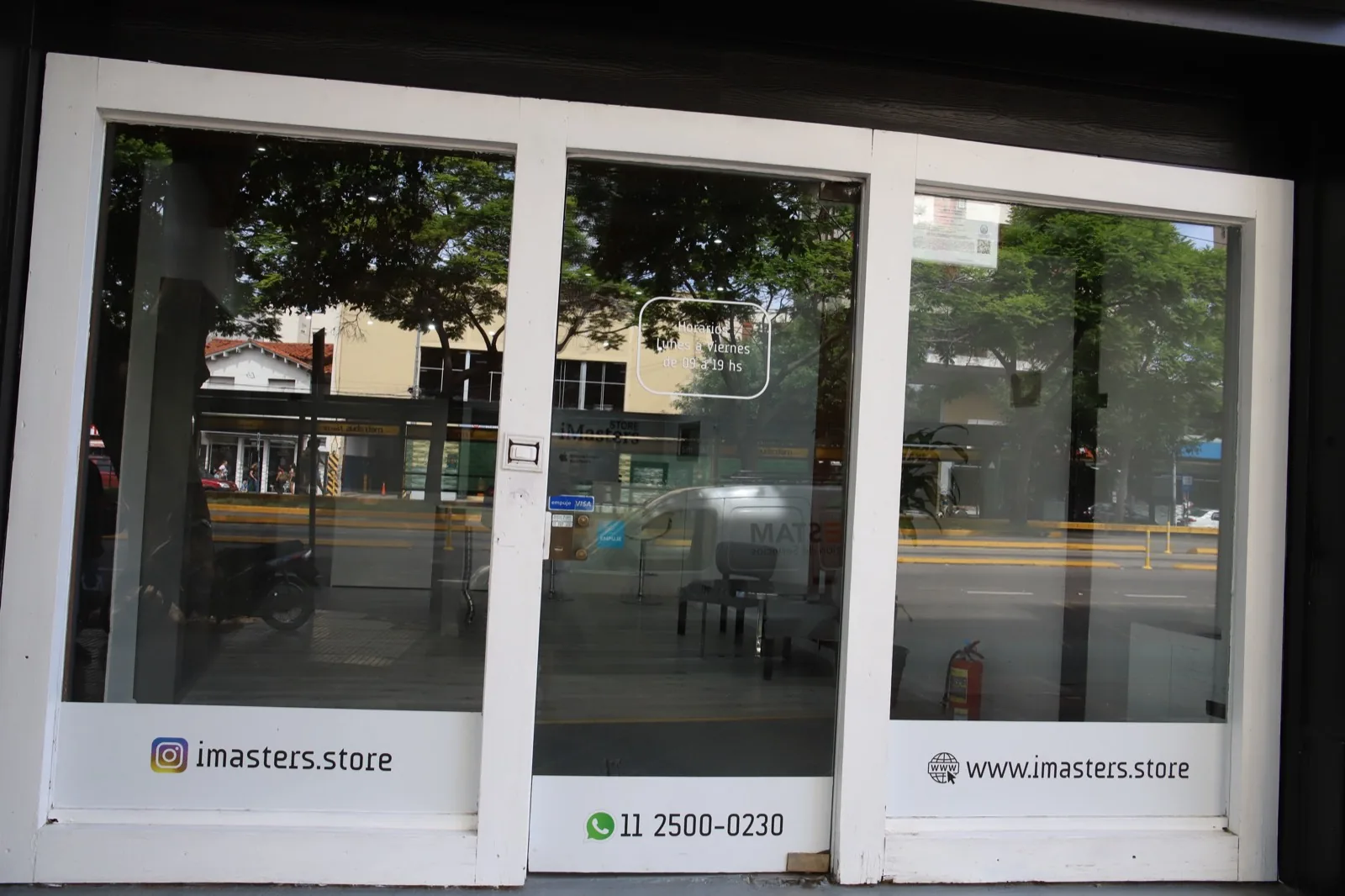 La vidriera de iMasters Store desde la vereda, con el horario de atención y las redes del local